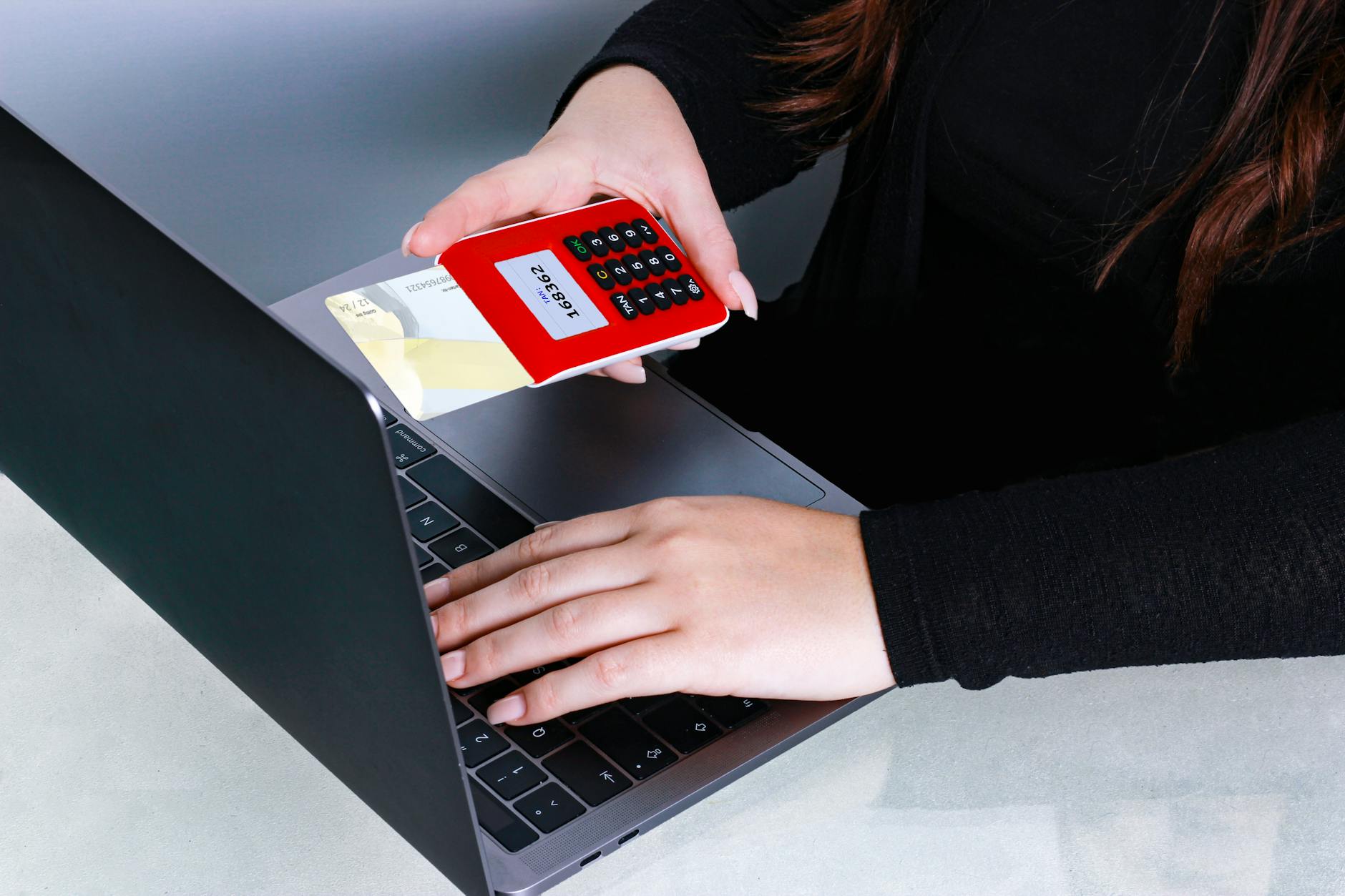 Dłonie przy laptopie wpisujące dane karty podczas płatności online