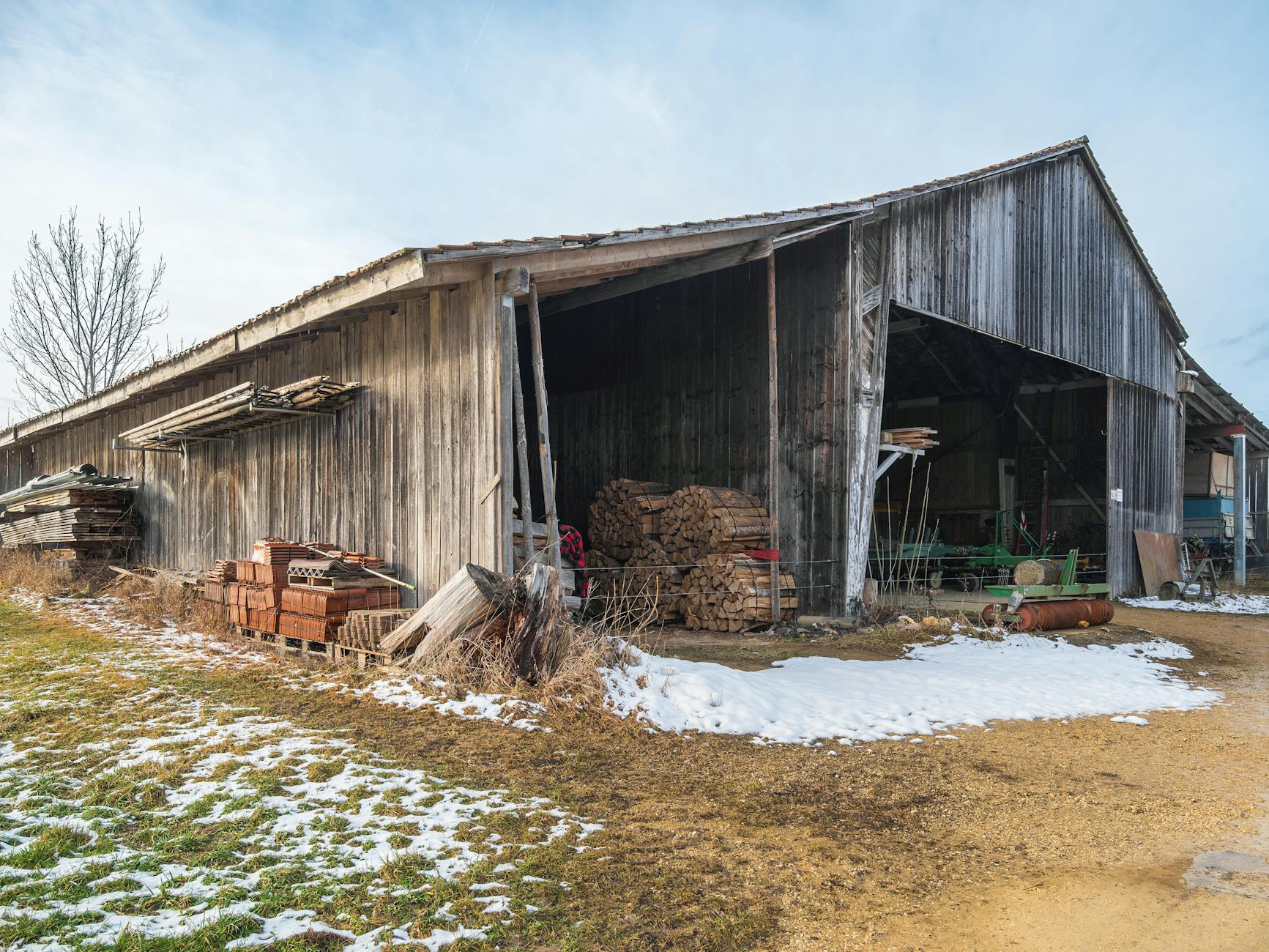 Drewniana stodoła z opałem w ośnieżonym, wiejskim krajobrazie