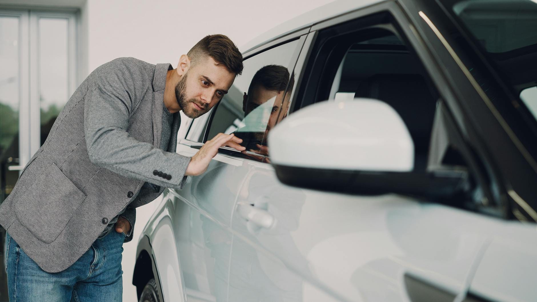 Mężczyzna dokładnie ogląda białe auto premium w salonie samochodowym