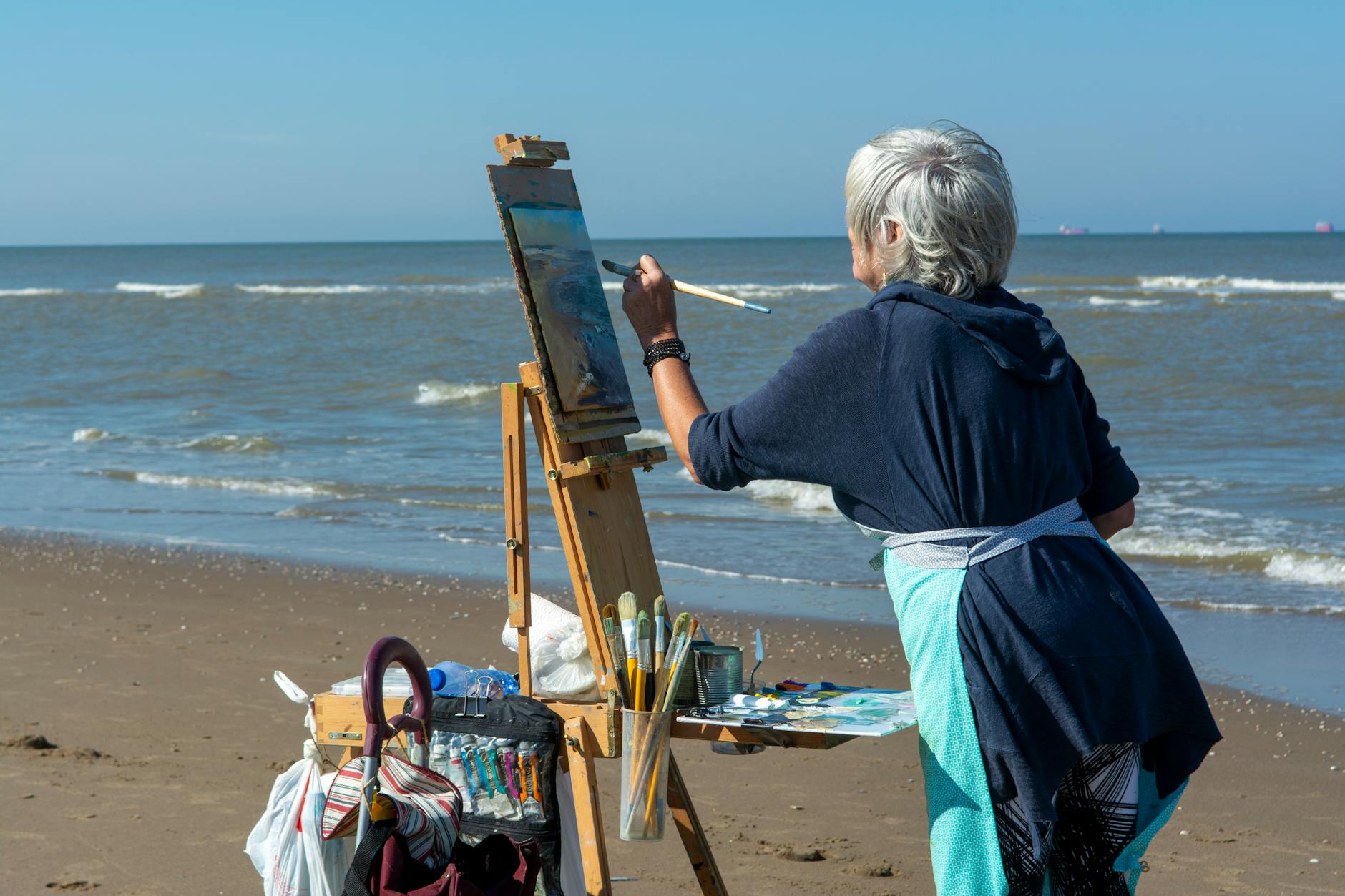 Starsza malarka maluje letni pejzaż nadmorski na plaży