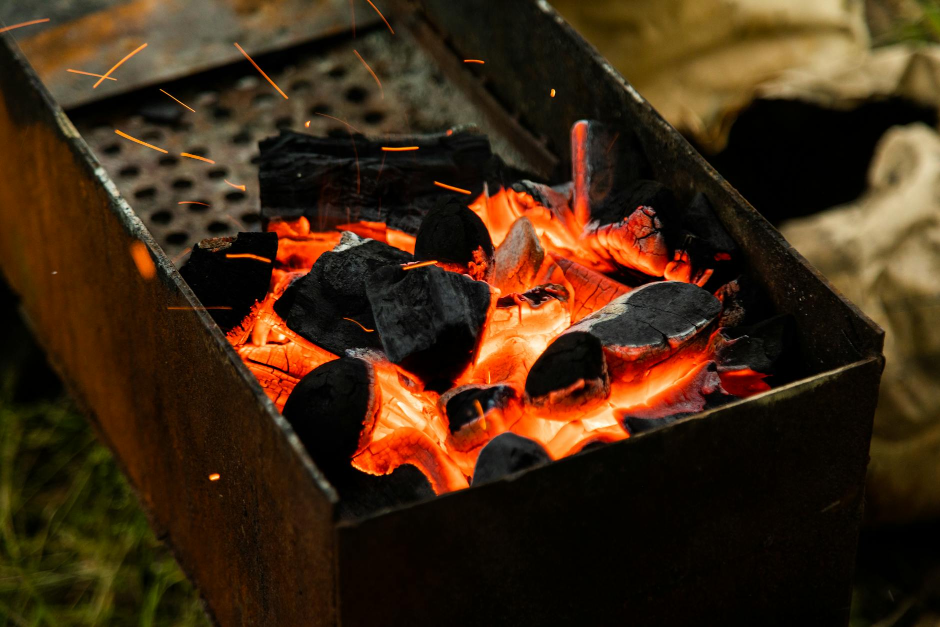 Żarzący się węgiel w grillu z widocznymi iskrami