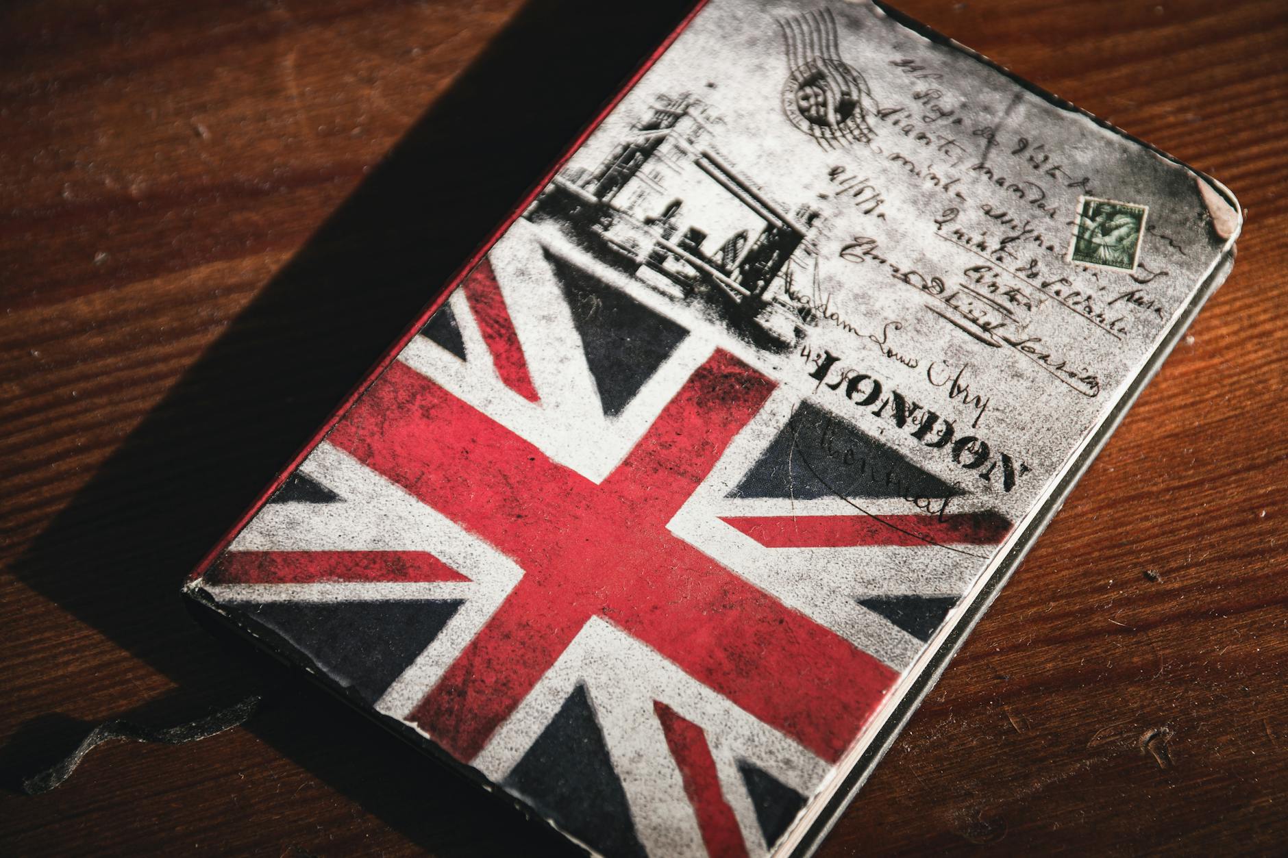 Stary notes z flagą brytyjską i widokówką Londynu na drewnianym stole
