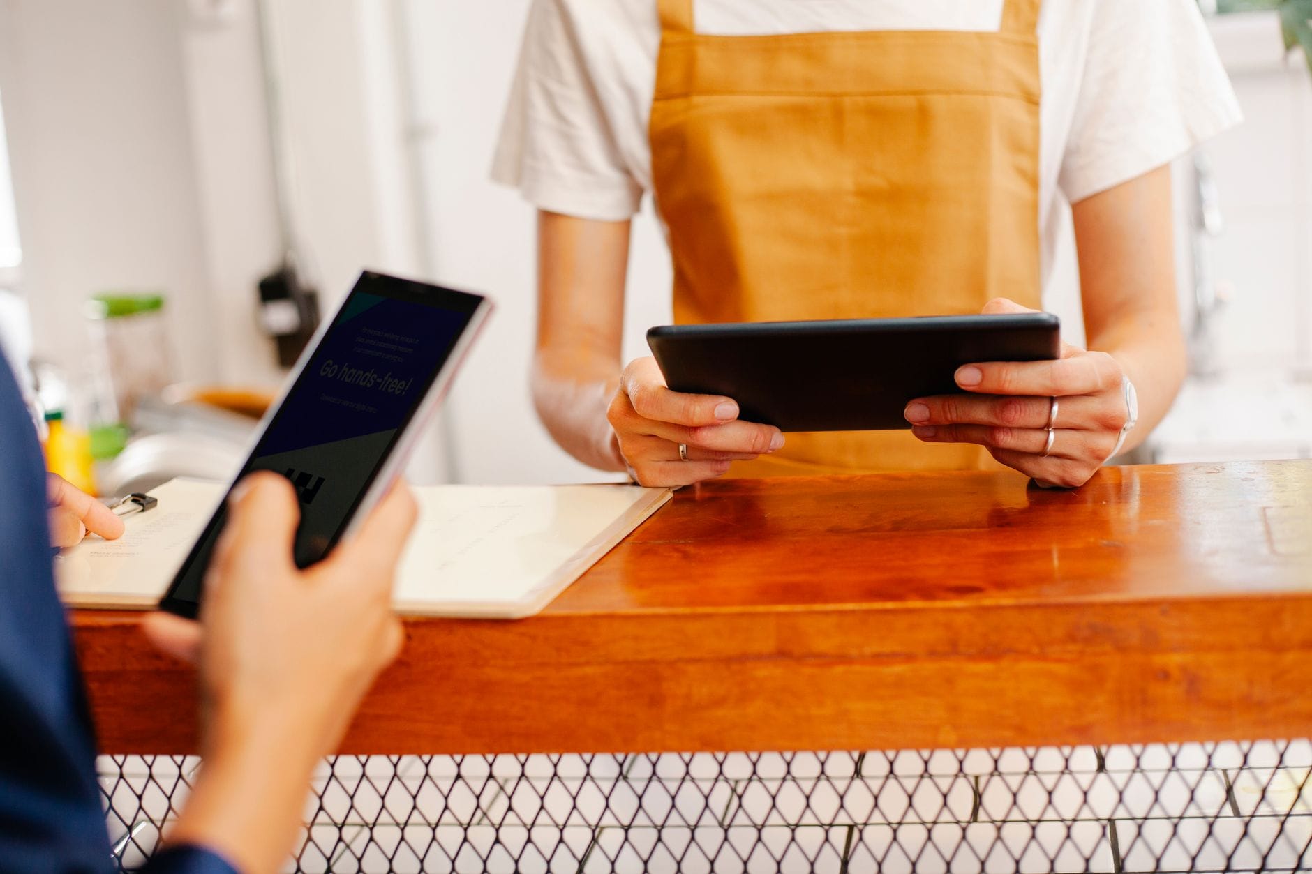Dwie kobiety przy stoliku w kawiarni korzystają z telefonu i tabletu