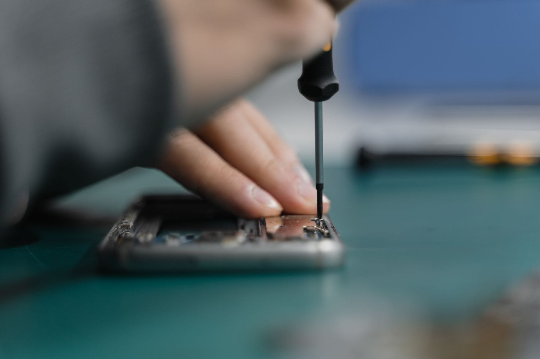 Zbliżenie na dłoń naprawiającą smartfon śrubokrętem